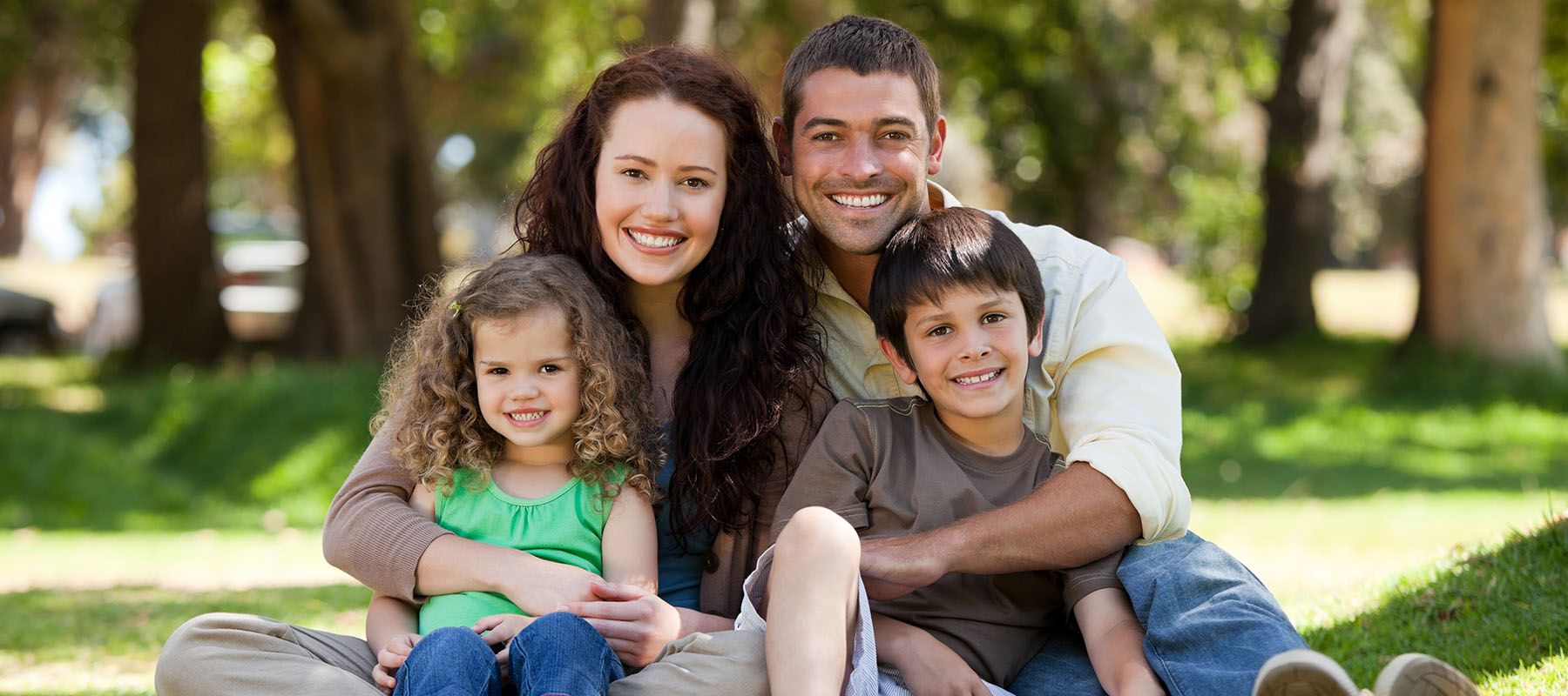 Photograph of smiling family sitting in the grass